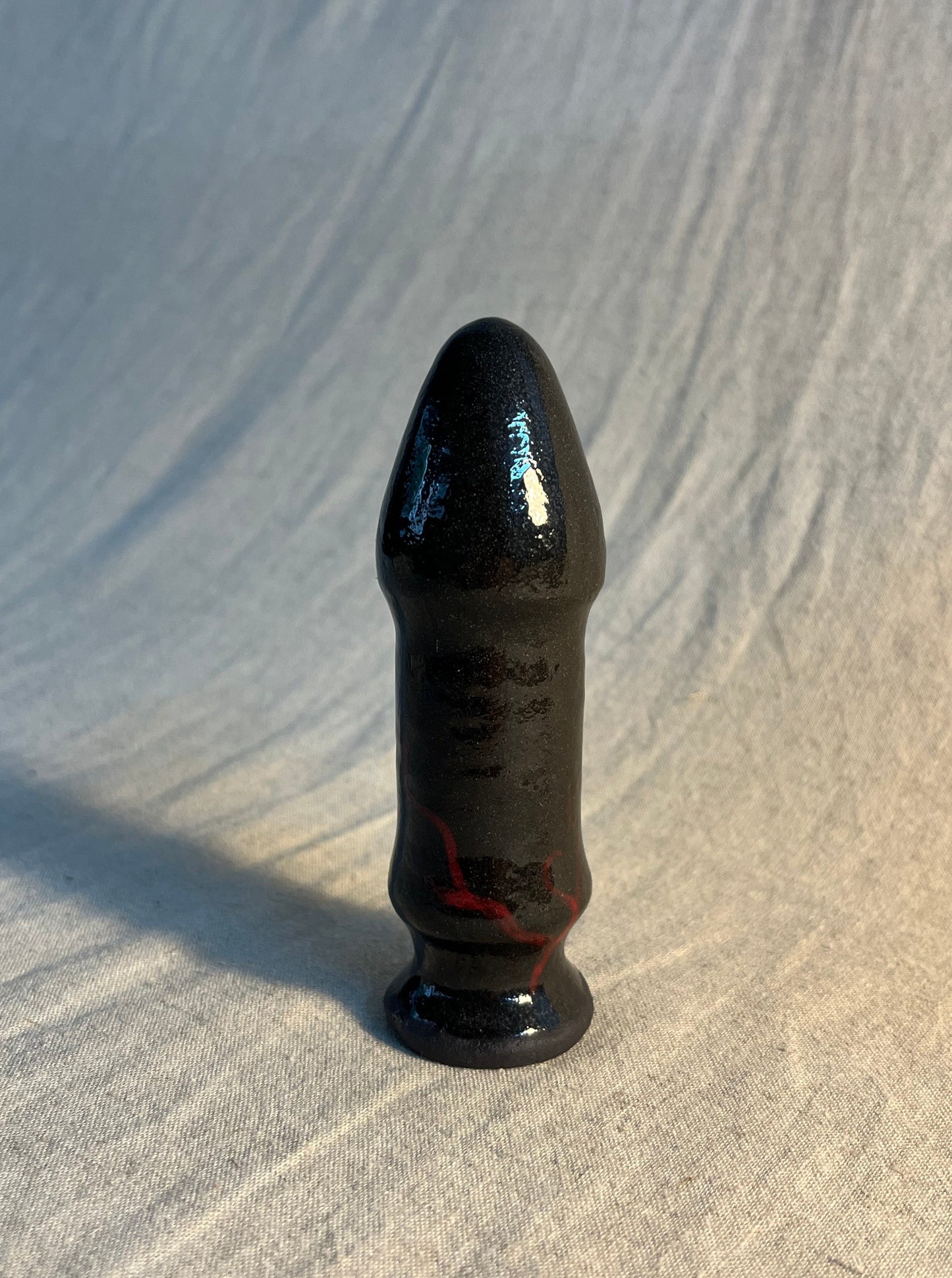 Phallus plug with vein detailing Hand made, one of one 10.5cm x 3.5cm Black stoneware, transparent glaze with red underglaze
